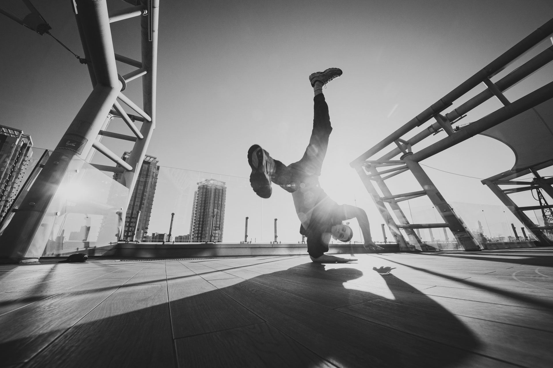Person macht Handstand auf einer Dachterrasse mit moderner Stadtarchitektur im Hintergrund